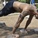 Athletic man performing elevated push-ups on rocks in a park setting.